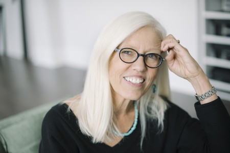 Author Margi Preus sitting in a chair and smiling